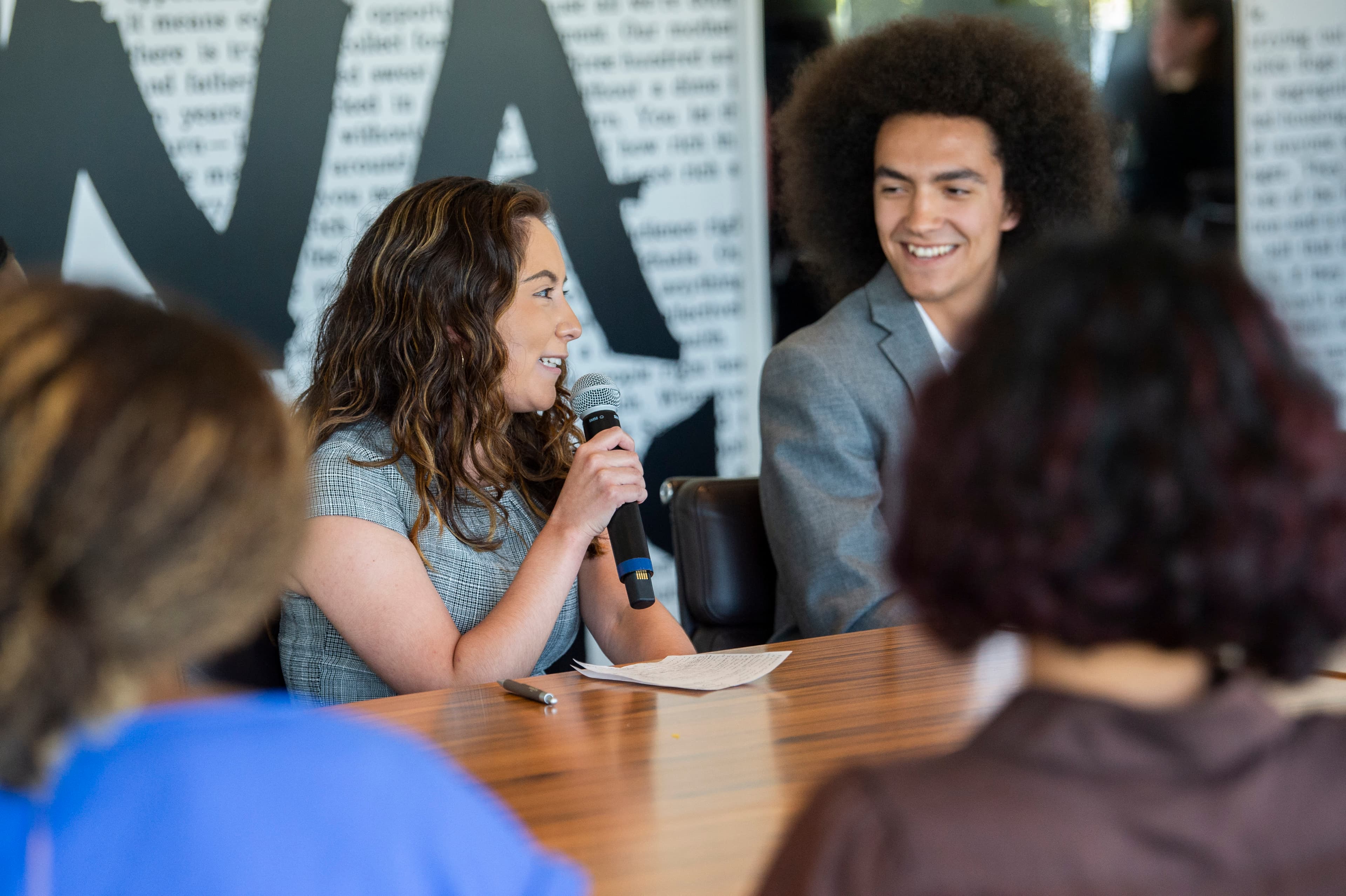 Two interns smiling and speaking at a table